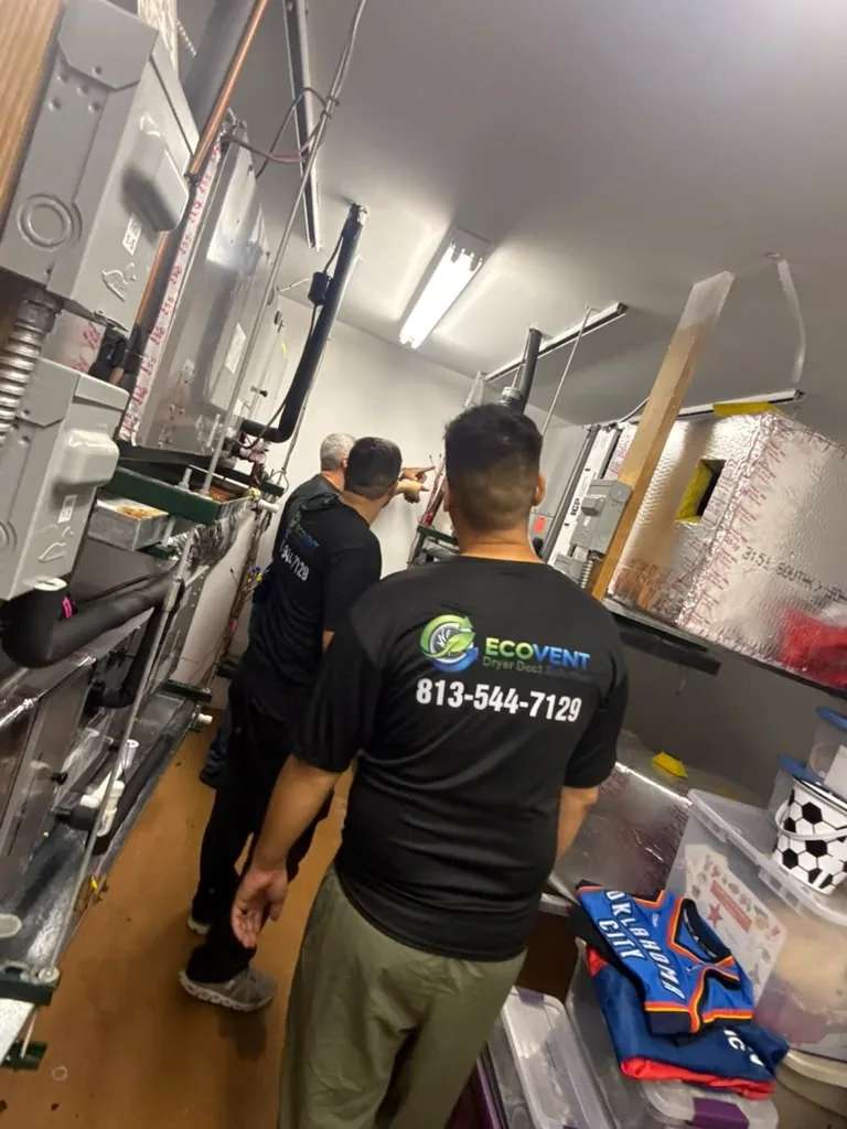 Three Ecovent technicians in company shirts look over the air handlers in a commercial mechanical room